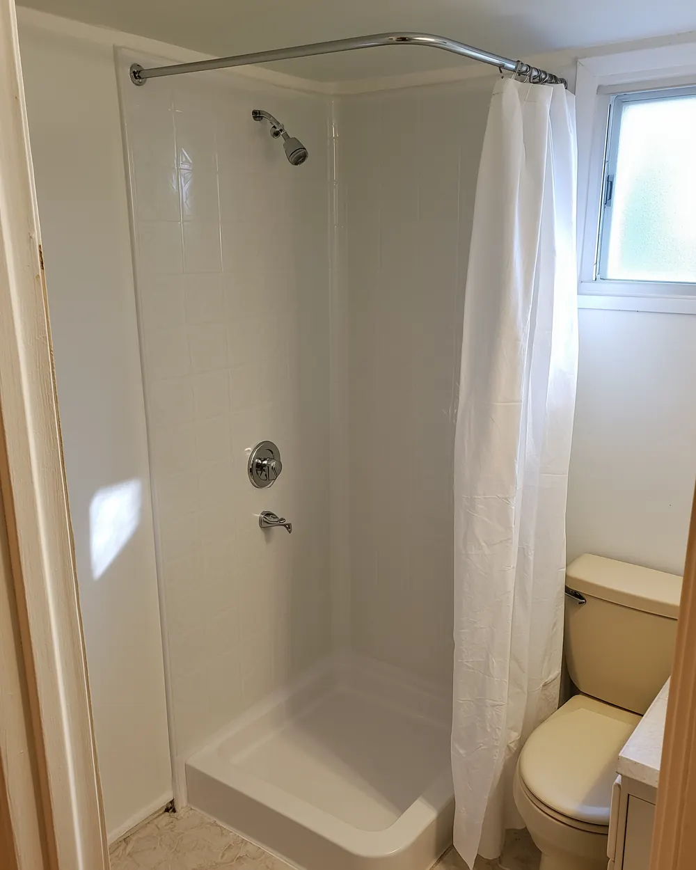 After: prefab acrylic shower surround with standard chrome fixtures