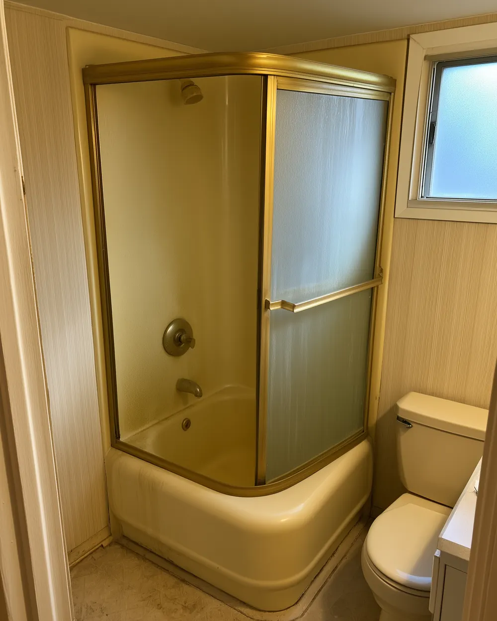 Before: dated tub-and-tile bathroom, prior to a prefab acrylic walk-in shower conversion